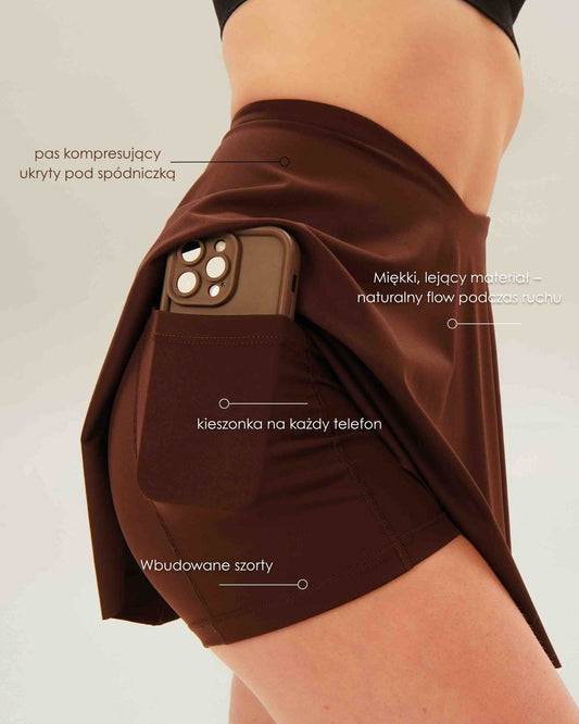 Infografika przedstawiająca funkcje brązowej spódniczki Glissmove – kompresyjne spodenki, kieszonka, wysoki stan, sportowy materiał